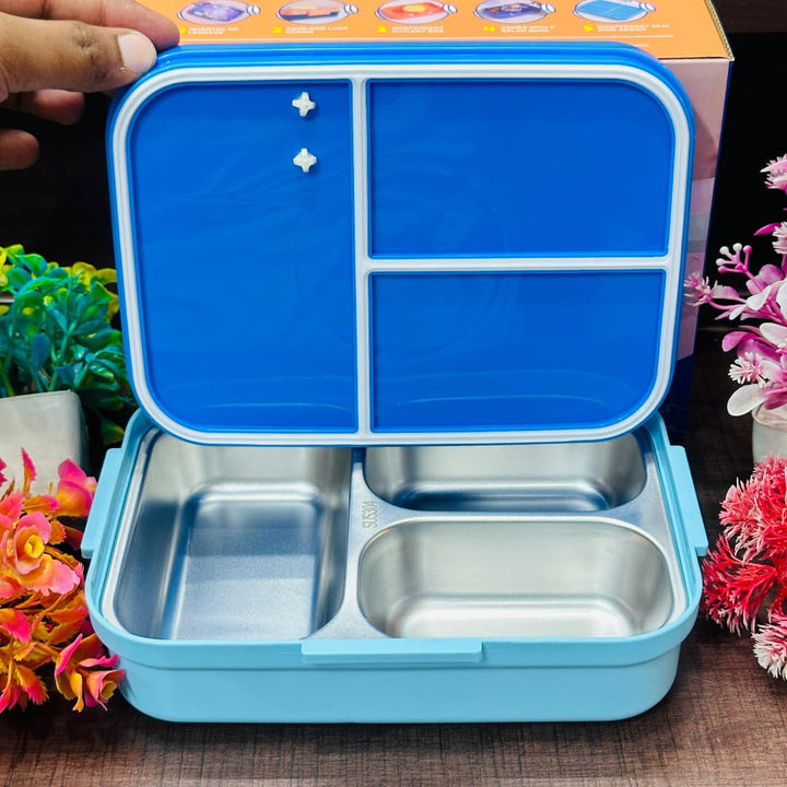 Blue and silver compartmentalized food container with floral decorations in the background