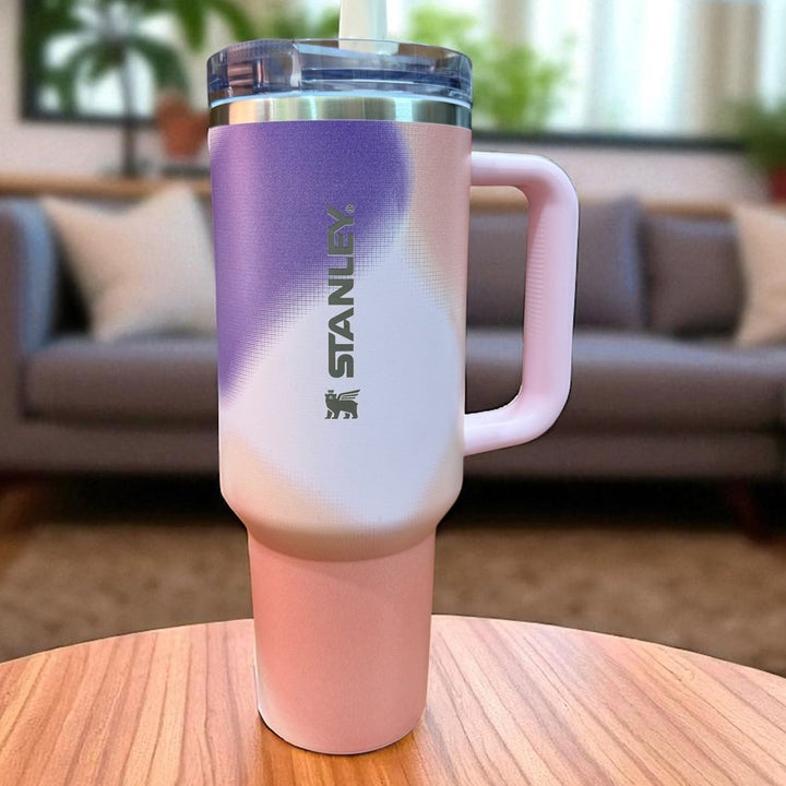 Pink and purple Stanley tumbler on a wooden table with a blurred living room background
