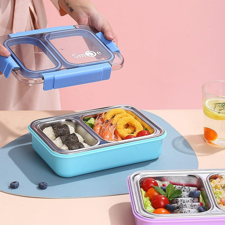 Blue bento box with food compartments on a pink background