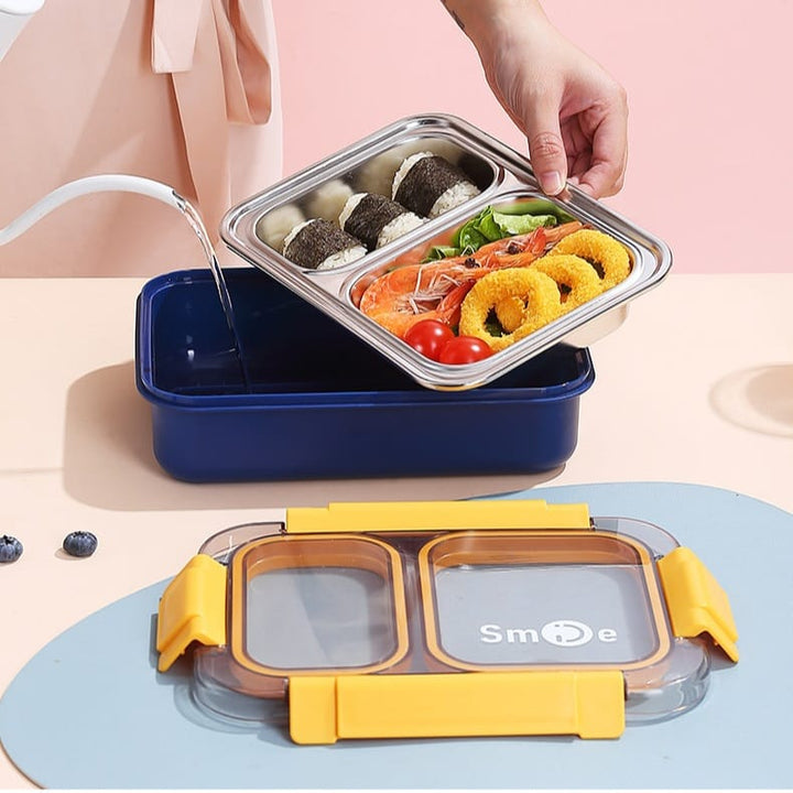 Bento box with compartments containing food items on a pink background