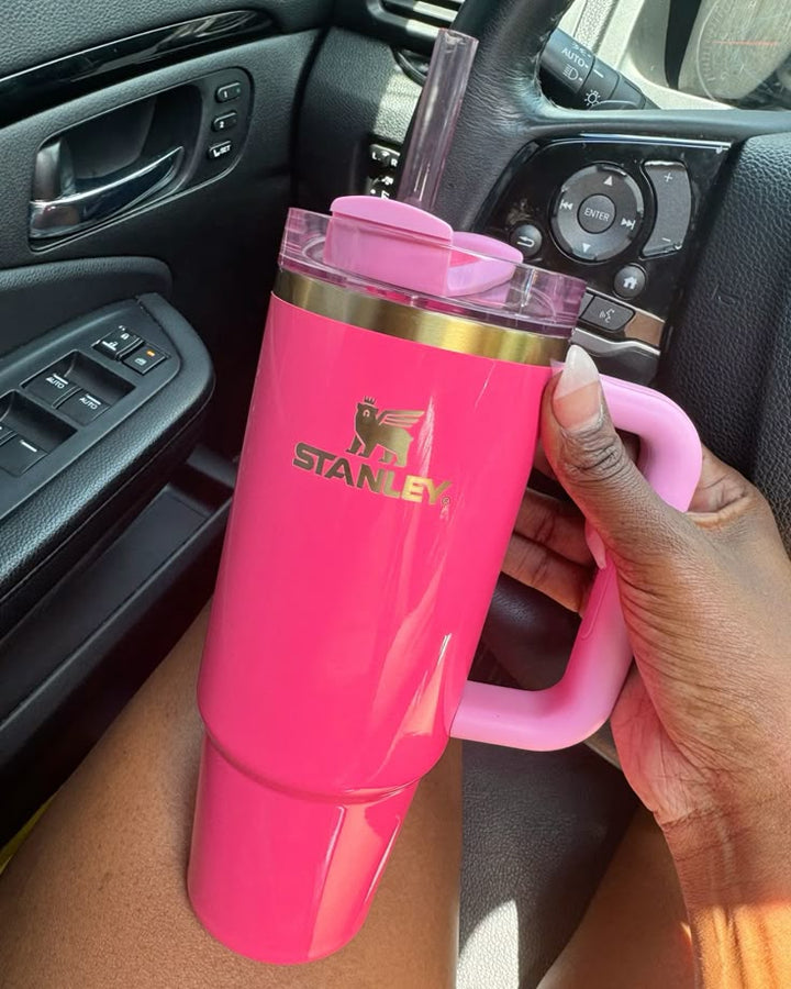 Pink Stanley mug held inside a car.