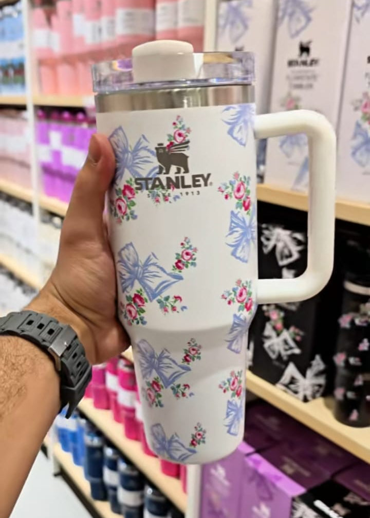 Hand holding a Stanley tumbler with floral design in a store setting