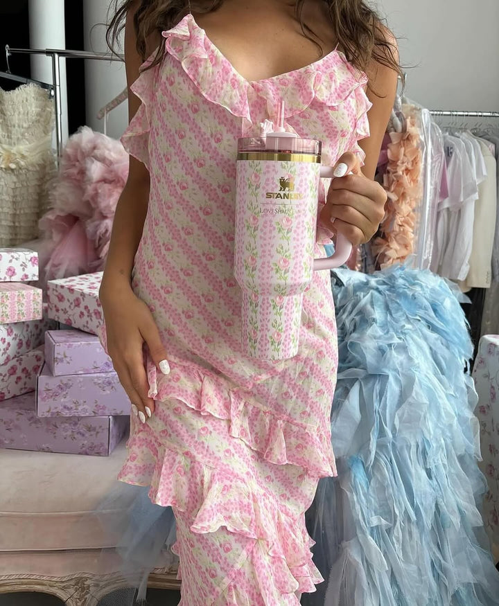 A person holding a Stanley x LoveShackFancy tumbler with a blush pink and gentian blue design, featuring LoveShackFancy's signature oversized bows.