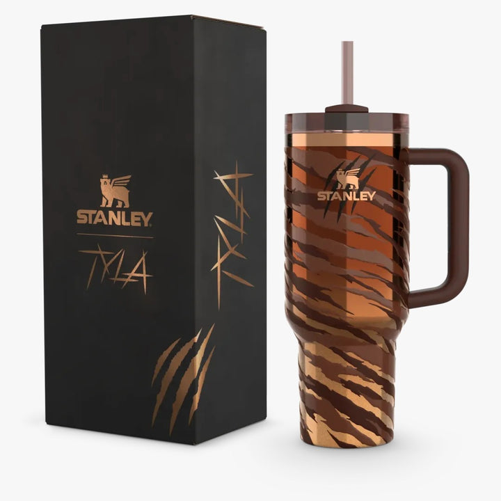 Brown and gold tumbler with handle and straw lid next to a black Stanley branded box on a white background