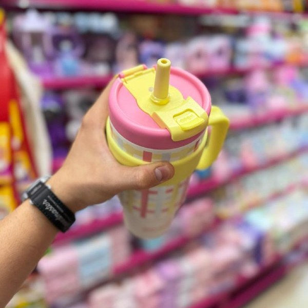 Hand holding a colorful cup with a straw in a store setting
